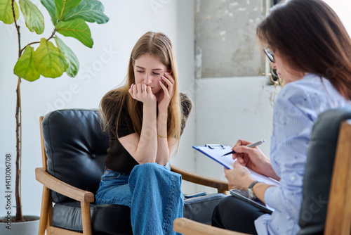 Sad upset young woman patient in therapy session in psychologist office