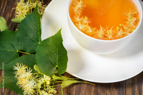 Linden tea with linden flowers in a white cup on a wooden background