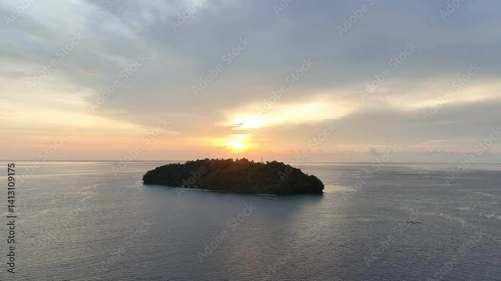 A serene sunrise silhouettes a small island just off the east coast of North Sulawesi, Indonesia. This beautiful area harbors extensive marine biodiversity. A serene sunrise silhouettes a small island just off the east coast of North Sulawesi, Indonesia. This beautiful area harbors extensive marine biodiversity.
