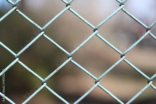 Obraz na płótnie Metal fence pattern view. Grid closeup shot. Chain link mesh. Structure in focus. Blurred soft background. Blue cold steel. Industrial feel mood. Geometric metal line design. w salonie