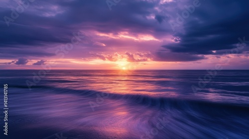 Vibrant sunset over calm ocean waves with dramatic clouds in the evening sky