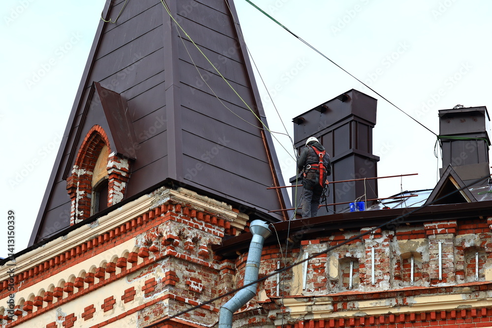 A person stands on the rooftop next to a clock tower, providing a sense of perspective and scale.