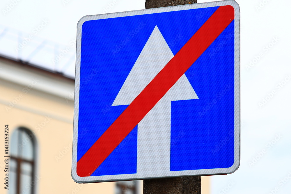 A blue and red street sign on a pole in the city.