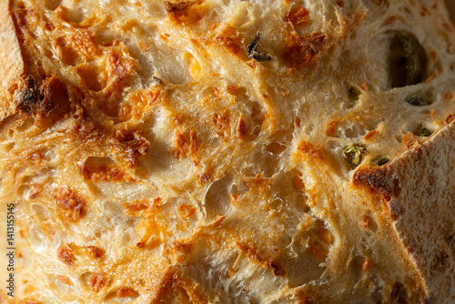 A top down view of a rustic olive sourdough boule, as a background.