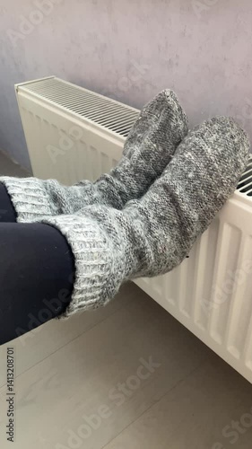 female legs in knitted socks on a battery, battery heating knob, heating in an apartment