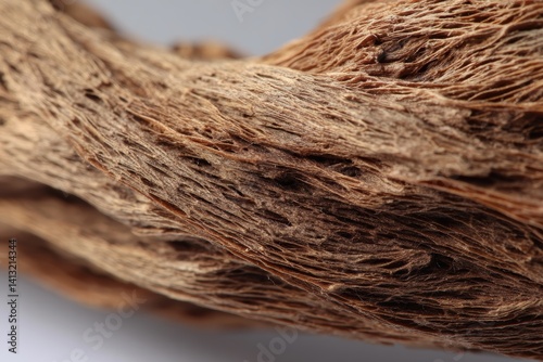 Twisted, fibrous texture of intertwined brown strands resembling a piece of dry bark or wood. The intricate details highlight the natural, rugged pattern of the material