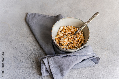 Close-up overhead view of a bowl of puffed wheat breakfast cereal on a table with a napkin