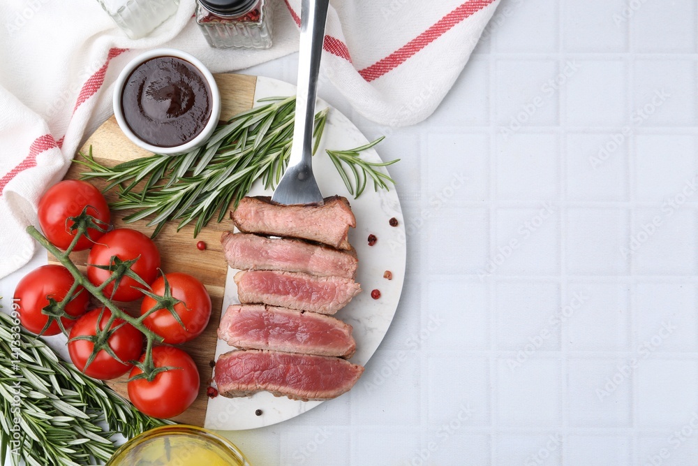 Delicious sliced beef tenderloin with different degrees of doneness, tomatoes, sauce and spices on light tiled table, top view. Space for text