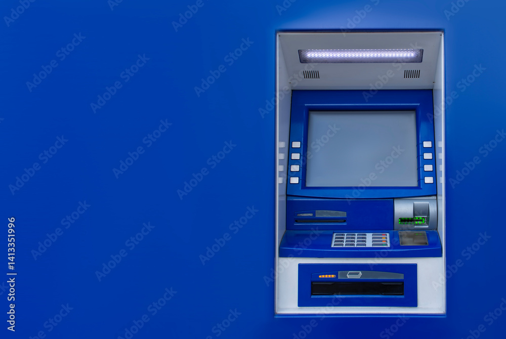 A blue ATM machine is mounted on a matching blue wall. Financial services and technology. A blue ATM machine is mounted on a matching blue wall. Financial services and technology.