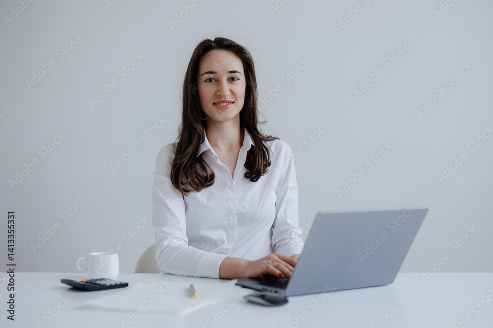 Young professional woman working on laptop in minimalist office setting during daytime Young professional woman working on laptop in minimalist office setting during daytime