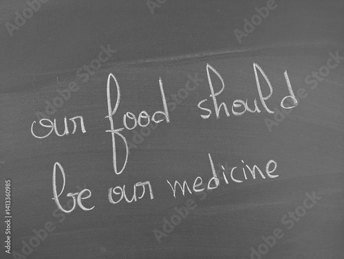 Health food concept illustration: Chalkboard with the inscription 'Our food should be our medicine' in white chalk.