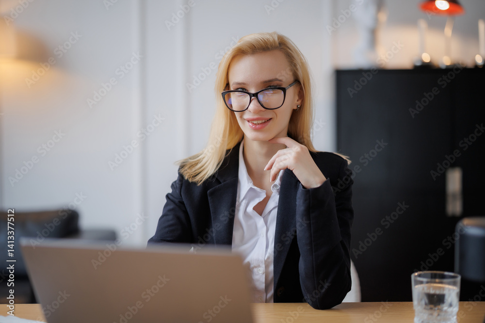 Woman smiling while working on laptop in modern office setting during day Woman smiling while working on laptop in modern office setting during day