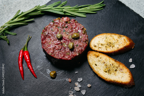 Beef tartare with capers and toast on slate. photo