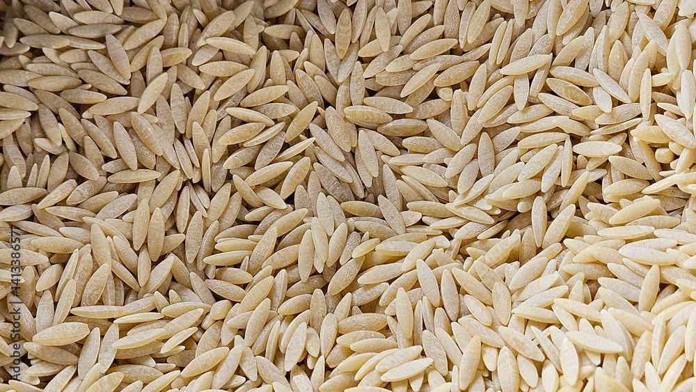 Close up of raw, uncooked orzo pasta. Grainy texture and unique, rice like shape. Healthy food lifestyle, home cooking, culinary, Mediterranean cuisine concept. Close up of raw, uncooked orzo pasta. Grainy texture and unique, rice like shape. Healthy food lifestyle, home cooking, culinary, Mediterranean cuisine concept.