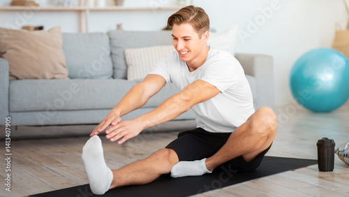 Fitness, pilates and gymnastics at home. Guy working on stretching with sports equipment in living room, free space