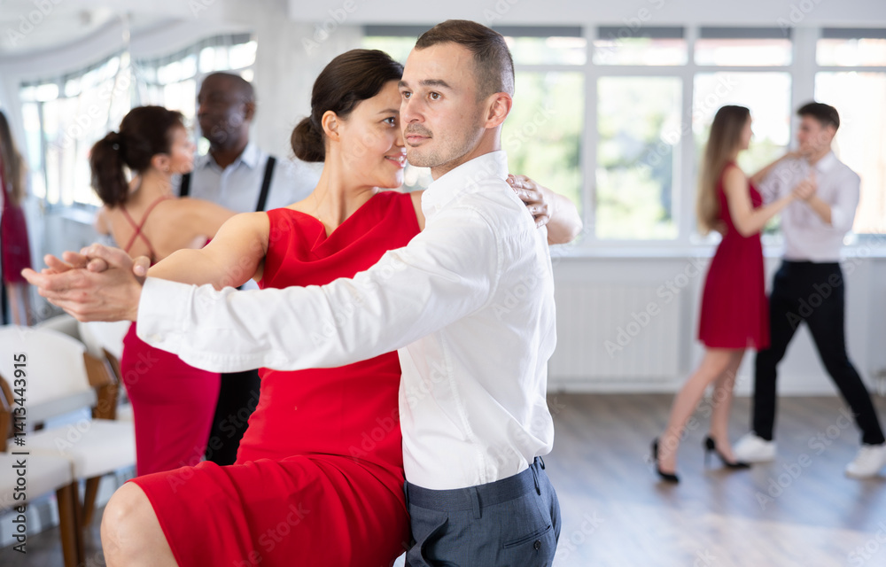 Obraz premium Young man engaged in dance hall with female partner and dances Latin rumba during celebration or party. Hobby, healthy lifestyle concept
