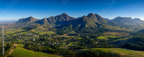 Breathtaking vista Somerset West's rolling hills, verdant vineyards, and majestic Helderberg Mountains, set against a vibrant blue sky near Cape Town, Western Cape