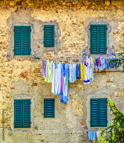 Greve in Chianti, Tuscany, Italy. Laundry hanging against a stone wall with green shuttered windows