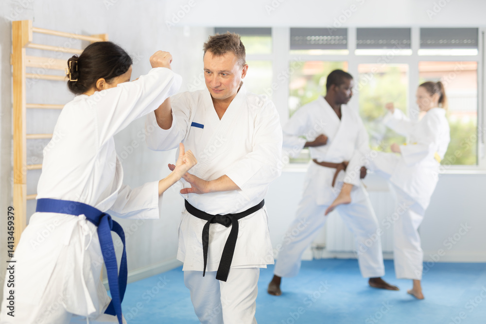 Obraz premium Woman and man in kimono sparring together in gym during karate training