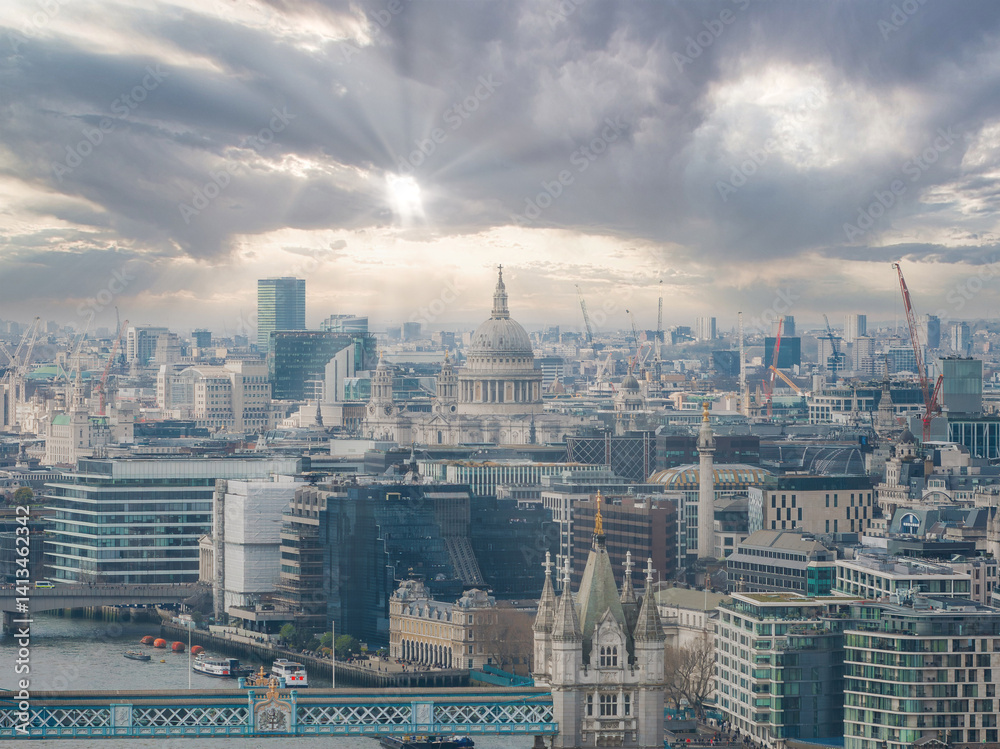 Aerial view of London with St. Paul's Cathedral at the center, Tower Bridge in the foreground, the Thames River, and a mix of architecture and construction.