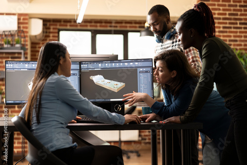 Obraz na płótnie Multiethnic team of digital engineers collaborating with asian 3D artist to resolve a geometry challenge. Diverse experts working together at office desk, discussing and enhancing a virtual assets. w salonie