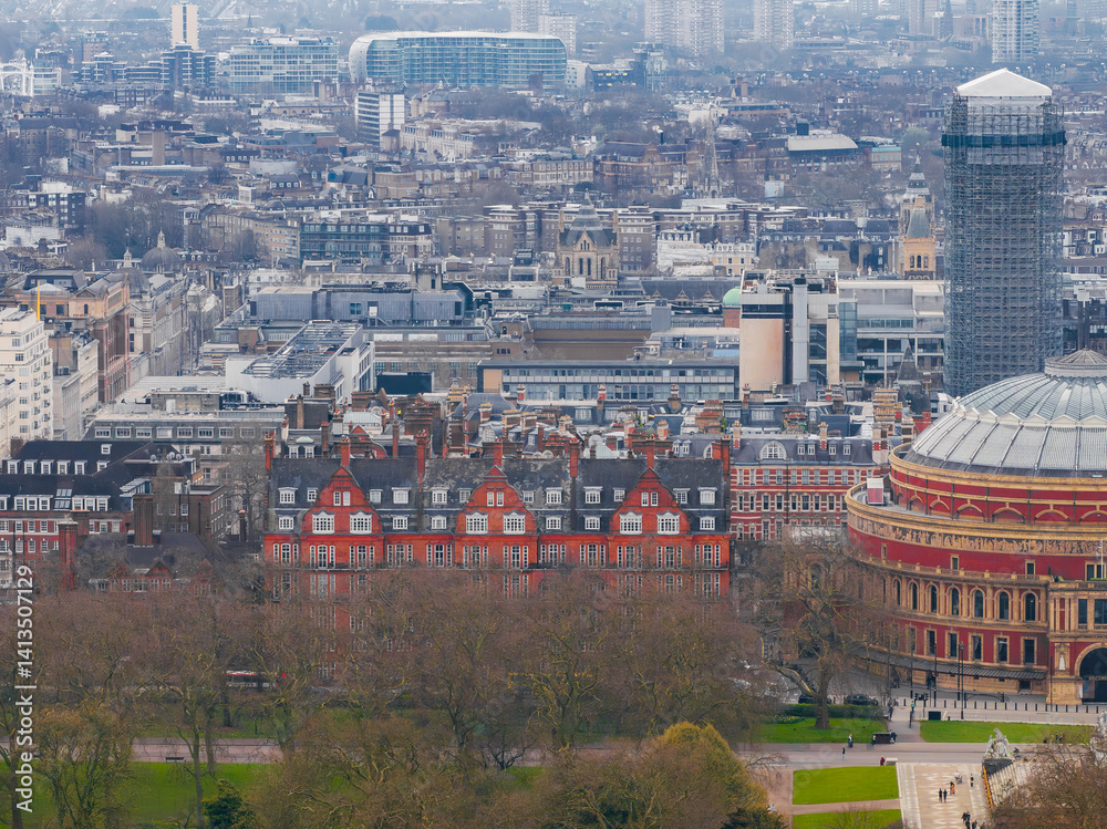 Aerial view of London with the Royal Albert Hall on the right, bare trees in the foreground, red brick buildings, and modern high rises in the distance.