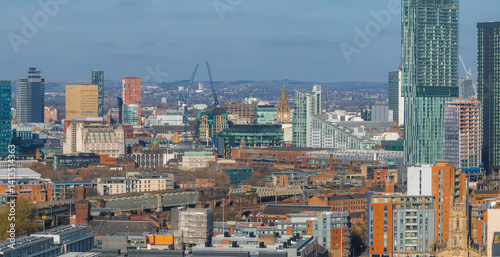 Obraz na płótnie Aerial view of Manchester, UK, showcasing skyscrapers like Beetham Tower, the Town Hall clock tower, red brick buildings, and distant hills. w salonie