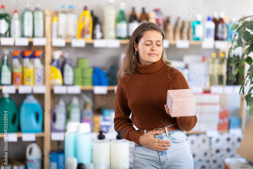 Young girl experiencing pain choosing feminine pads in large supermarket