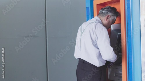 senior businessman is upset that he can't withdraw cash from an ATM. His salary isn't on schedule