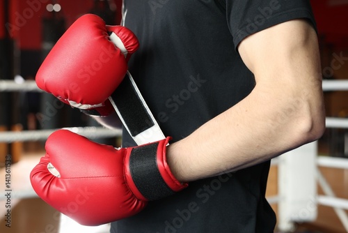 Obraz na płótnie Man putting on protective boxing gloves in training center, closeup w salonie