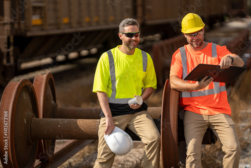 Railway workers checking railway track is level. engineer wearing a safety vest standing confidently on the railway tracks. Shipping worker controlling shipping cargo containers departure