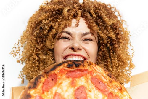 Photos Joyful woman with curly hair smiling while holding a delicious pizza, showcasing