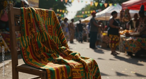 Vibrant Kente Cloth Draped on Wooden Chair at a Busy African Market