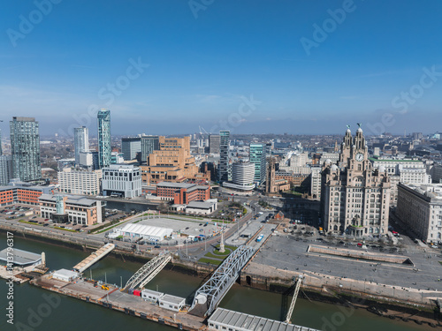 Obraz na płótnie Aerial view of Liverpool featuring the Royal Liver Building, waterfront docks, a bridge, modern high rises, and historic architecture under a clear blue sky. w salonie