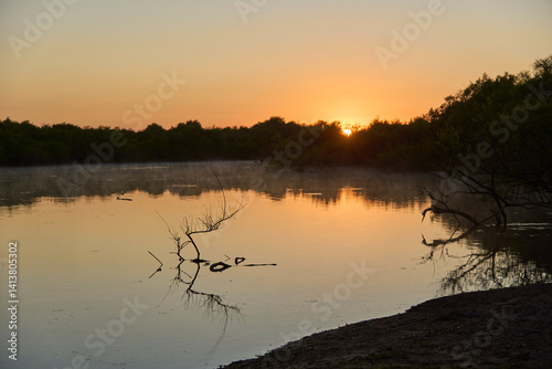 Sunrise scene, orange sunlight reflecting on the surface of the water in Los Loros Creek, El Palmar National Park, Entre Rios, Argentina.