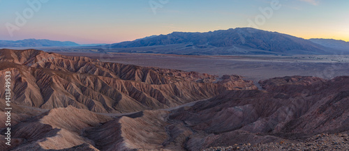 Eroded arid desert badlands of Death Valley National Park at sunset.  The Tucki Mountains rise above Mesquite Flat Sand Dunes on this colorful evening.