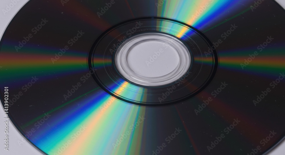 Close up view of a compact disc showing rainbow reflection and center hole on a white surface Close up view of a compact disc showing rainbow reflection and center hole on a white surface