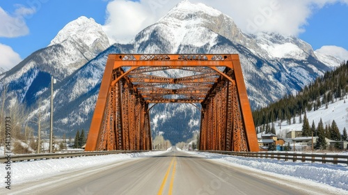 Rustic metal bridge spans a snowy mountain road