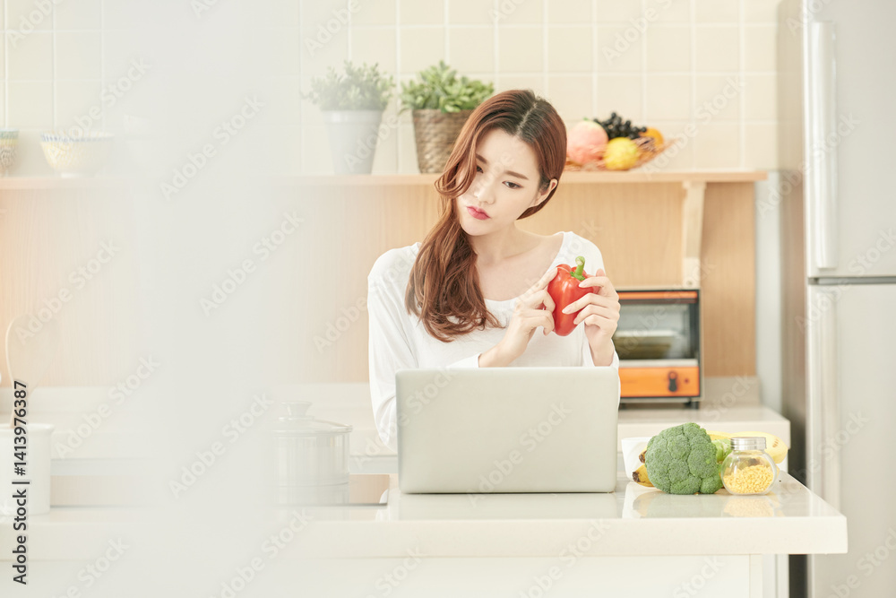 Young Woman Cooking at Home, Searching Recipe Online with Red Bell Pepper Young Woman Cooking at Home, Searching Recipe Online with Red Bell Pepper
