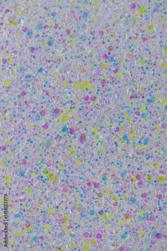 Full frame macro abstract texture background of sparkling pastel purple, yellow and blue glitter surface with copy space