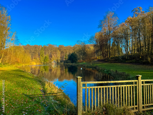  Scenic autumn lake view in waterloo, belgium with trees and old fence