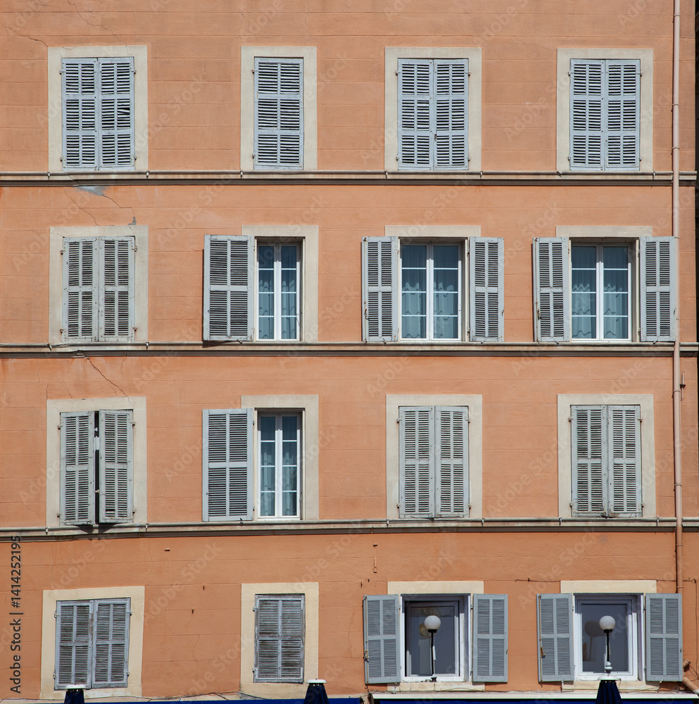 typical facade of an old hotel with open and closed wooden shutters typical facade of an old hotel with open and closed wooden shutters