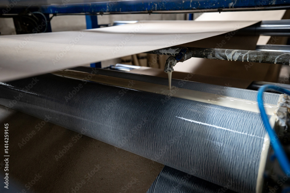 A production line for gluing thin sheets of paper from rolls at a bookbinding cardboard production facility. The company uses recycled material (waste paper) to make book covers.