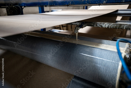 Obraz na płótnie A production line for gluing thin sheets of paper from rolls at a bookbinding cardboard production facility. The company uses recycled material (waste paper) to make book covers. w salonie
