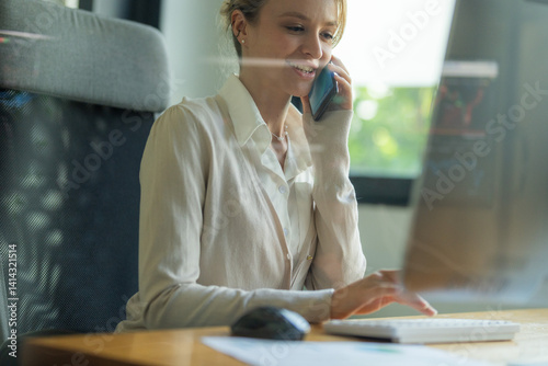 Wallpaper Mural Professional woman on phone call while working at a desk in a modern office setting during daytime Torontodigital.ca