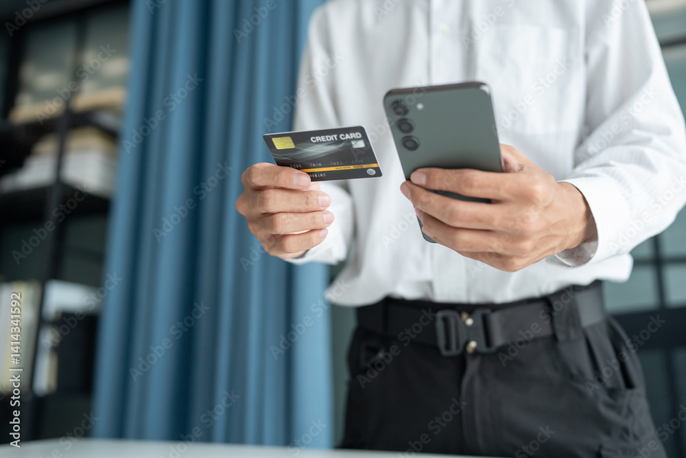 Asian Man paying with credit card on smart phone at office. Male Using Smartphone for Shopping electronic wallet Online Asian Man paying with credit card on smart phone at office. Male Using Smartphone for Shopping electronic wallet Online