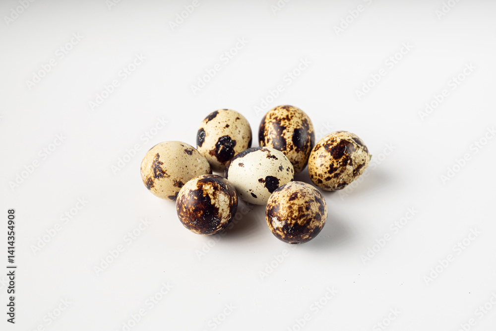 Fototapeta premium A close-up shot of seven speckled quail eggs arranged on a clean, white background.