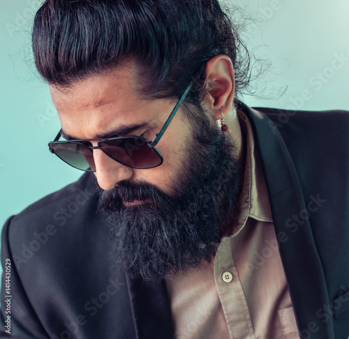 Slika na platnu Close-up portrait of a man with long, dark hair styled in a topknot, a full, dark beard, and sunglasses