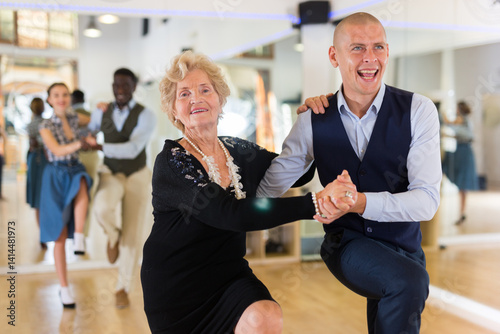 Senior woman and younger man dancing swing in studio