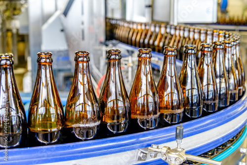Bottling process at a beverage production facility showcasing autoclave machinery and conveyor belts in action during daylight hours